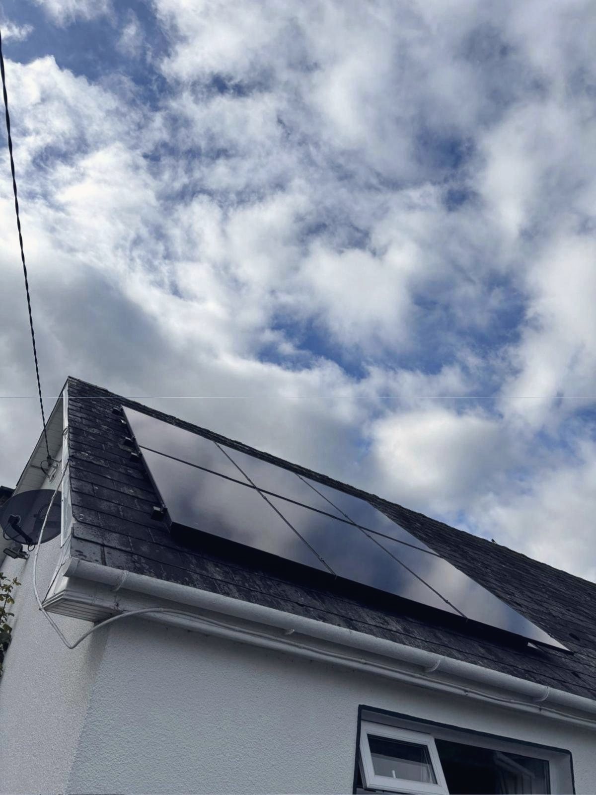 Looking up at the panels on the slate roof against a bright, cloudy sky